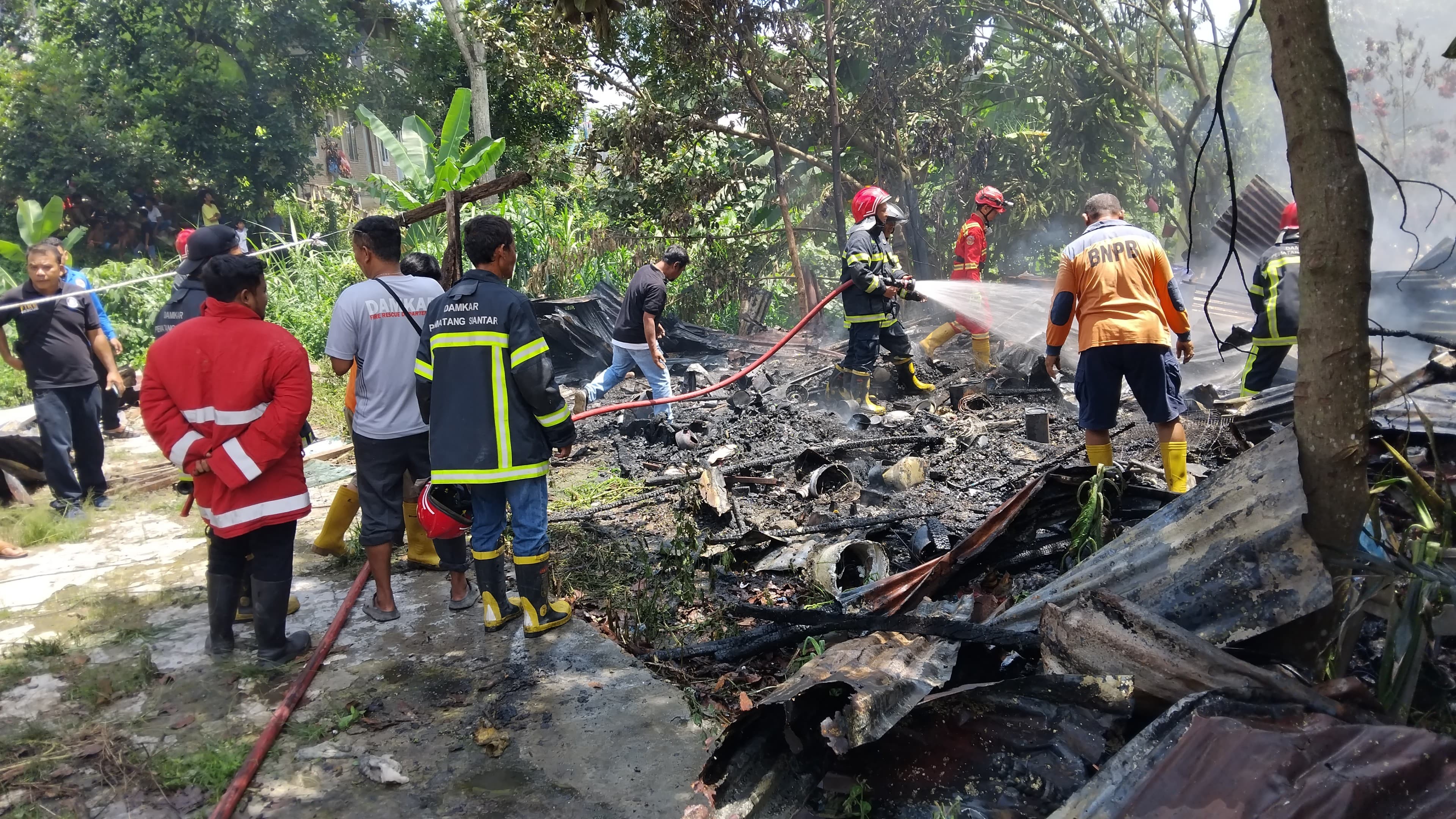 Personil Dinas Pemadam Kebakaran dan Penyelamatan melaksanakan pemadaman kebakaran rumah di  Jl. Nag