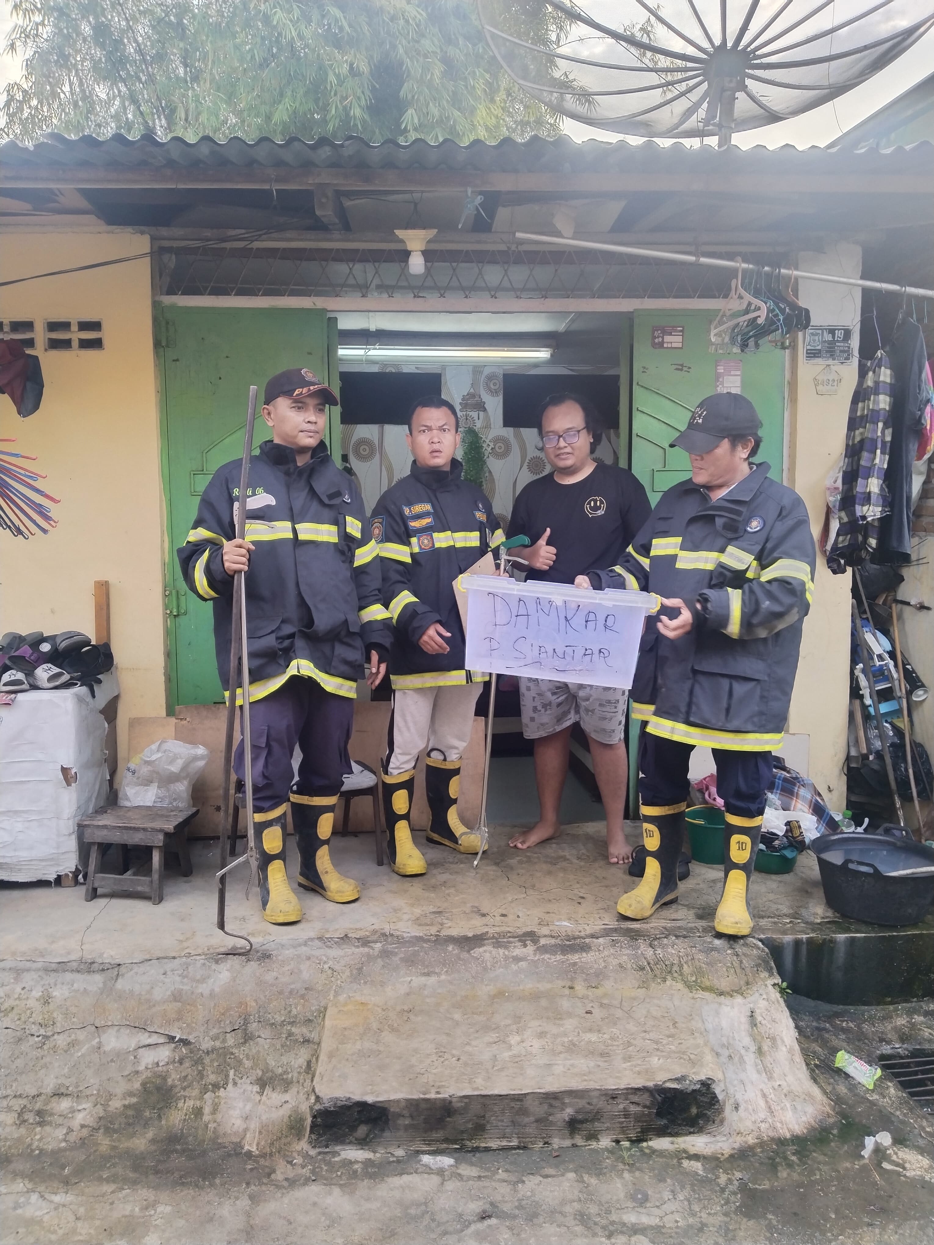 Personil Dinas Pemadam Kebakaran dan Penyelamatan berhasil mengevakuasi seekor ular di rumah warga  