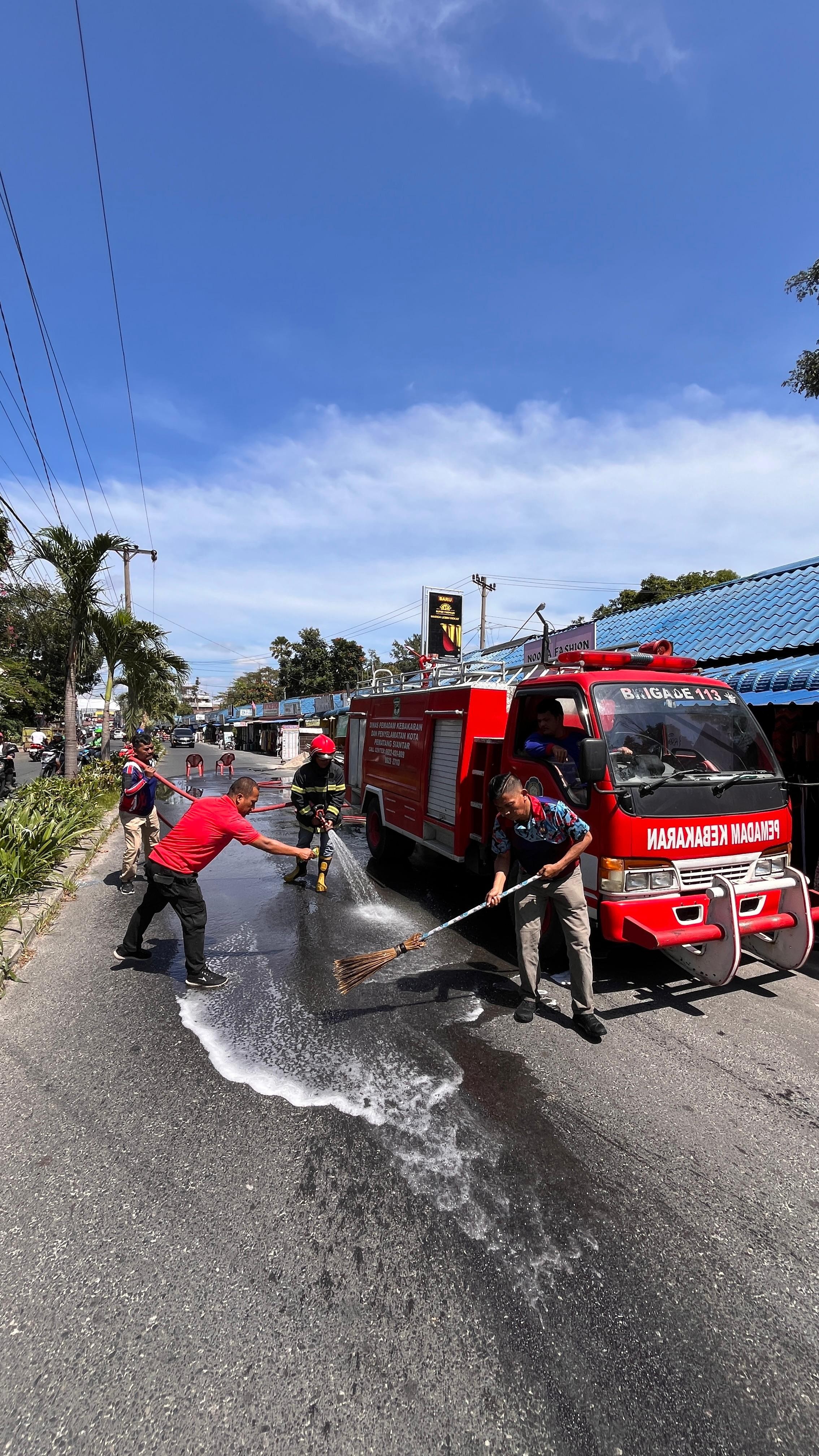 Personil Dinas Pemadam Kebakaran dan Penyelamatan melaksanakan penyiraman tumpahan oli yang membahay